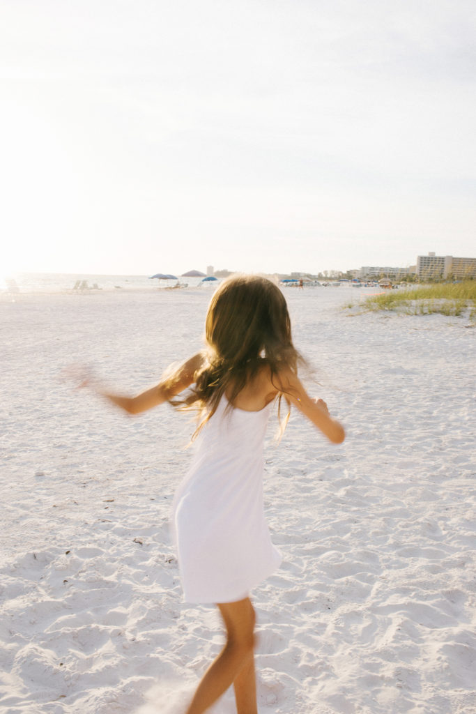 Girl dancing on beach in white dress Elle Baker Photography