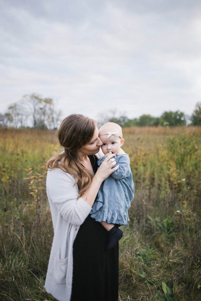Large family sessions with Elle Baker Photography near Chicago. a mom and baby cuddling in an open field wearing Zara clothing