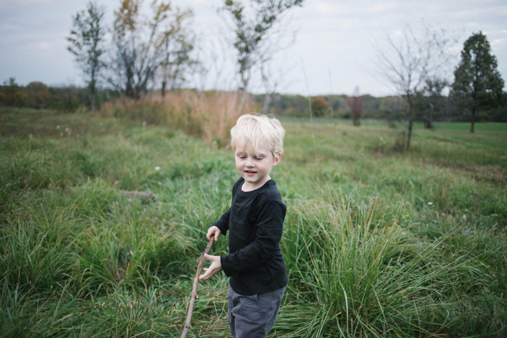 Large family sessions with Elle Baker Photography near Chicago. A young boy playing with a stick wearing Zara clothing