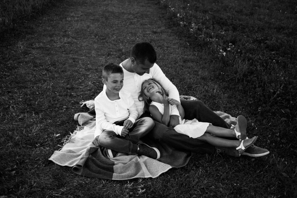 let's go fly a kite | Elle Baker Photography | Family of three on blanket laughing outdoors 