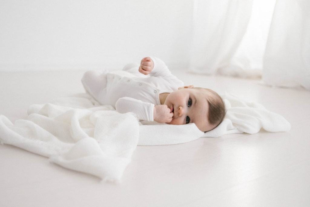 Six Month Milestone Sessions including a gorgeous baby boy in white pajamas and photographed in a beautiful white studio space.  