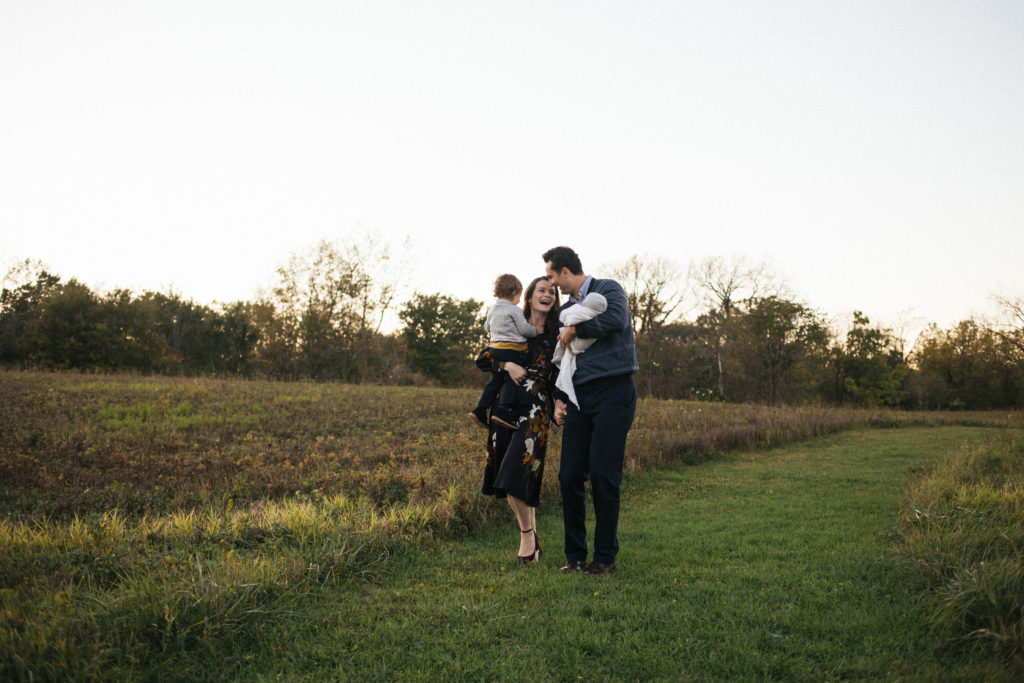 Naperville Illinois Forest Preserve, Photos by Elle Baker Photography, family of four walking at sunset in a open field, dad holds newborn and mom holds toddler son