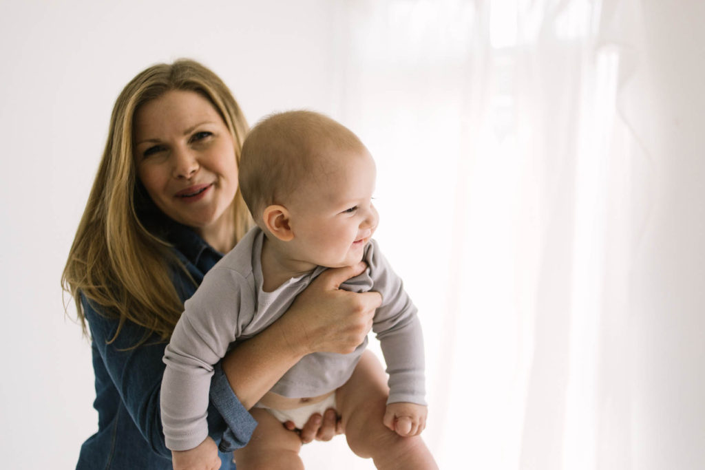 Tips For a Successful Baby Milestone Session, Chicago baby photographer, Photos by Elle Baker Photography, mom holding baby boy playing super baby in white studio in Homer Glen Illinois