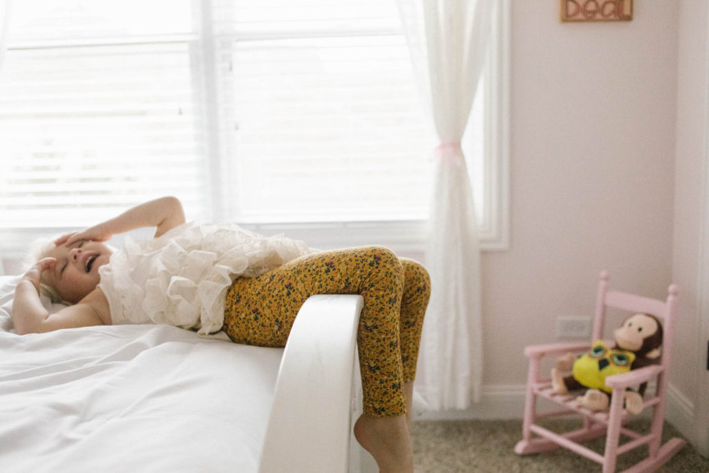 In home lifestyle session, Photos by Elle Baker Photography, Chicago photographer, a little girl sitting on her bed in a pink bedroom