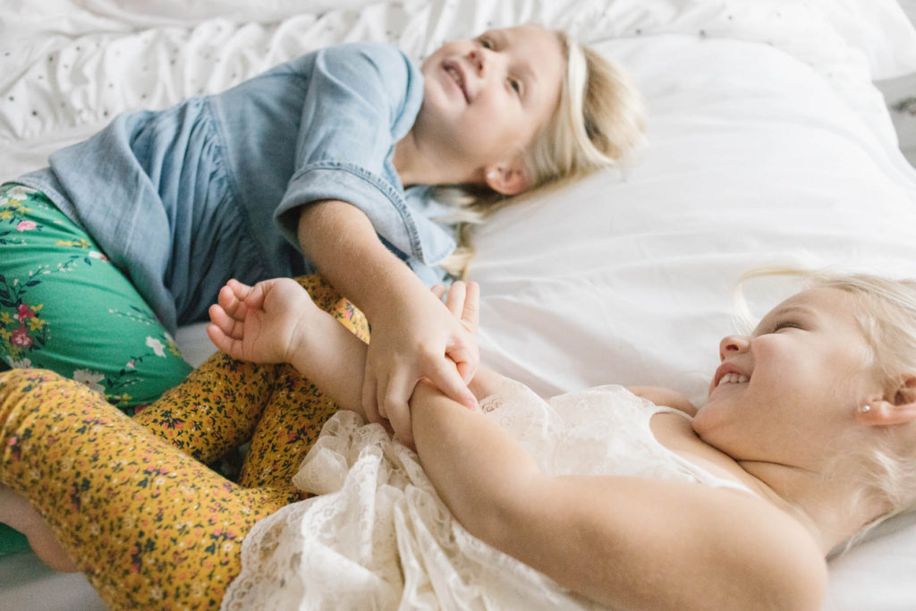 Chicago newborn and family lifestyle photographer, Elle Baker Photography, sibling sisters playing on bed during home session