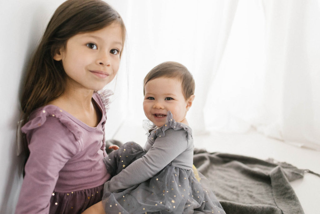 Family Photographer in Naperville, Illinois, Photo by Elle Baker Photography, two sisters modeling matching Ele story gray glitter tulle dress, what to wear for holiday inspired session