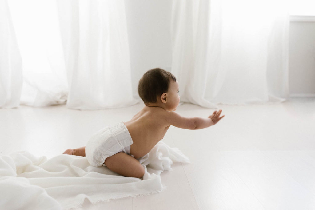 Simple and natural baby session, Photo by Elle Baker Photography, baby girl in white studio space in Chicago crawling and waving