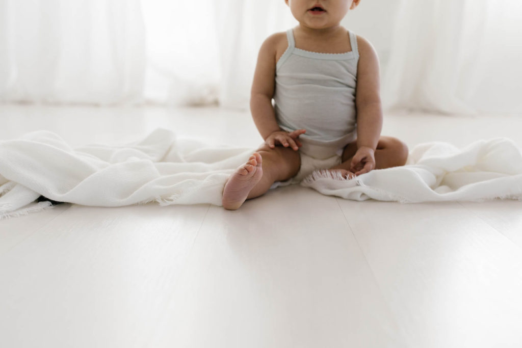 simple and natural baby session, Photo by Elle Baker Photography, baby girl's foot in white studio space in Chicago smiling