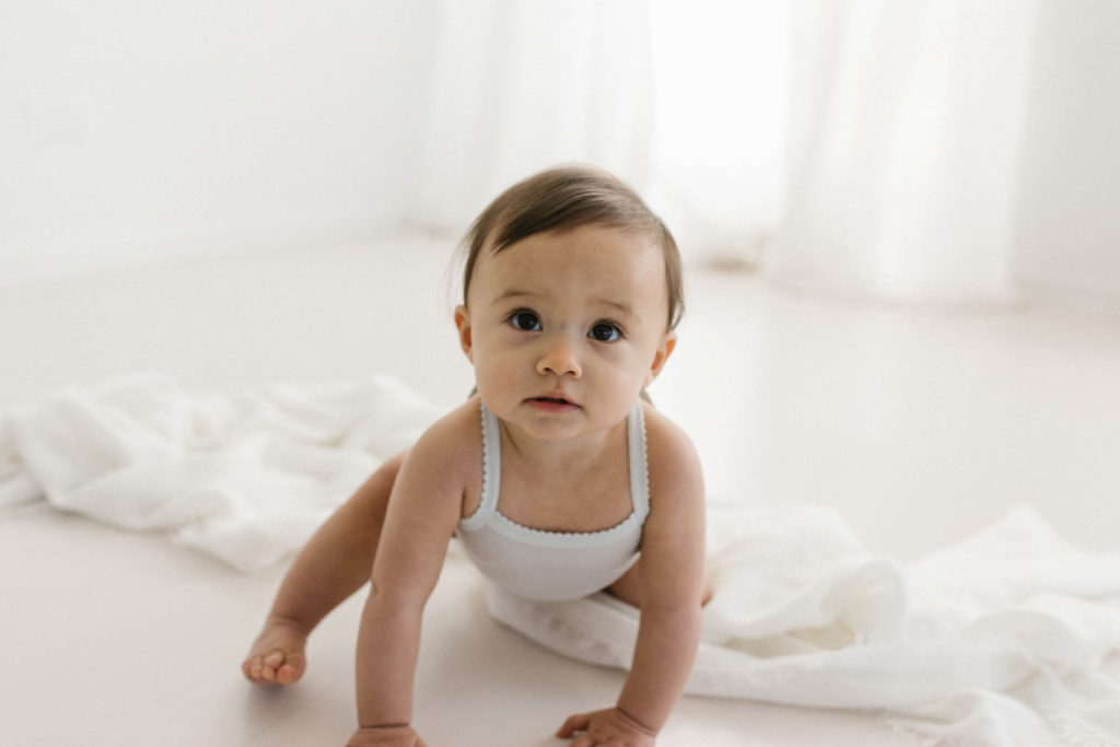 Simple and natural baby session, Photo by Elle Baker Photography, baby in a white cotton onsie in a white studio