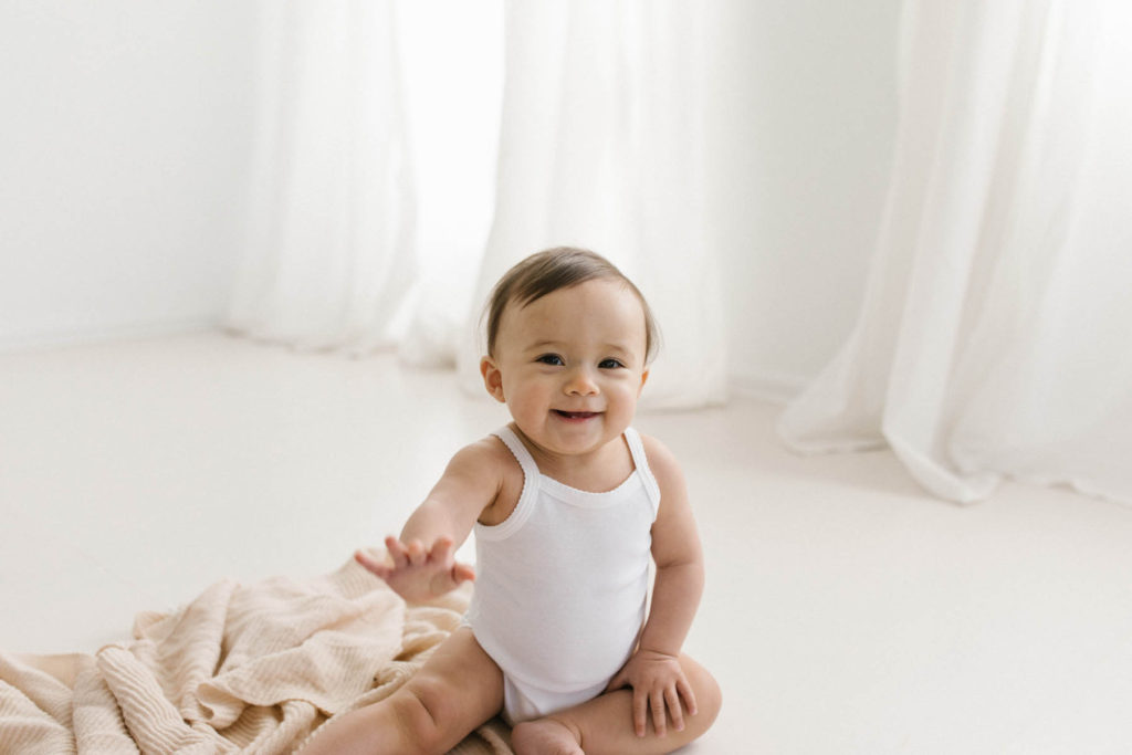 Simple and natural baby session, Photo by Elle Baker Photography, baby girl in white studio space in Chicago waving her hands