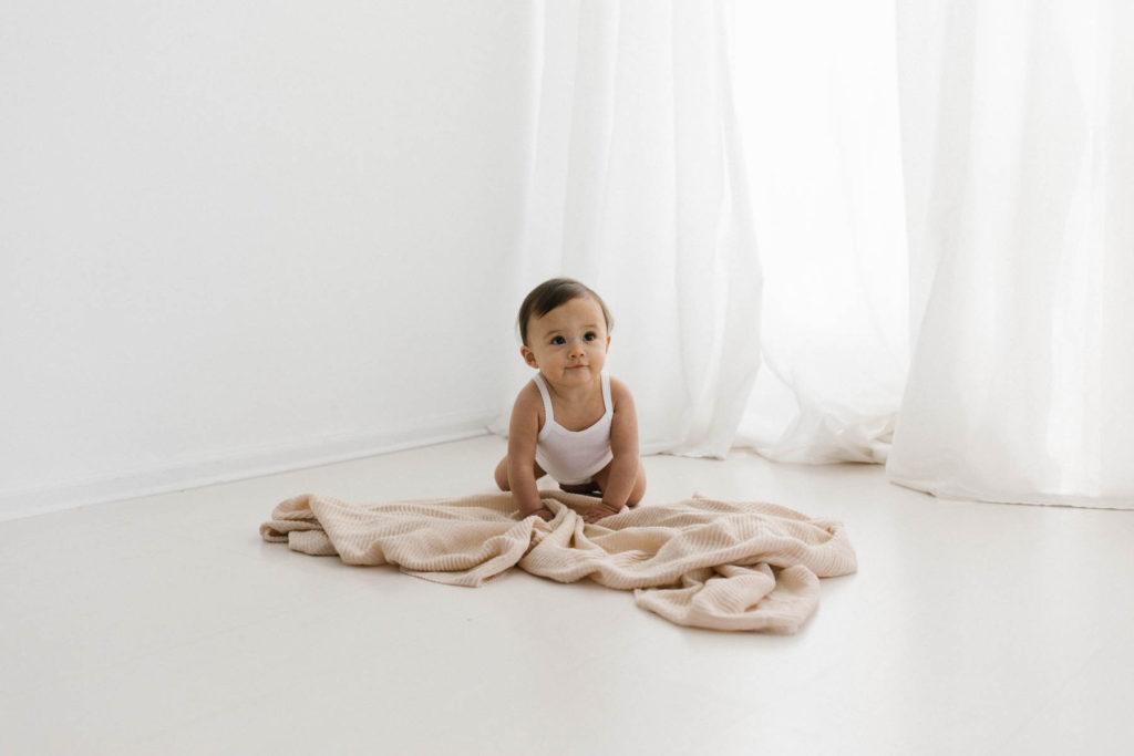 Simple and natural baby session, Photo by Elle Baker Photography, baby in a white cotton onsie in a white studio and natural set up