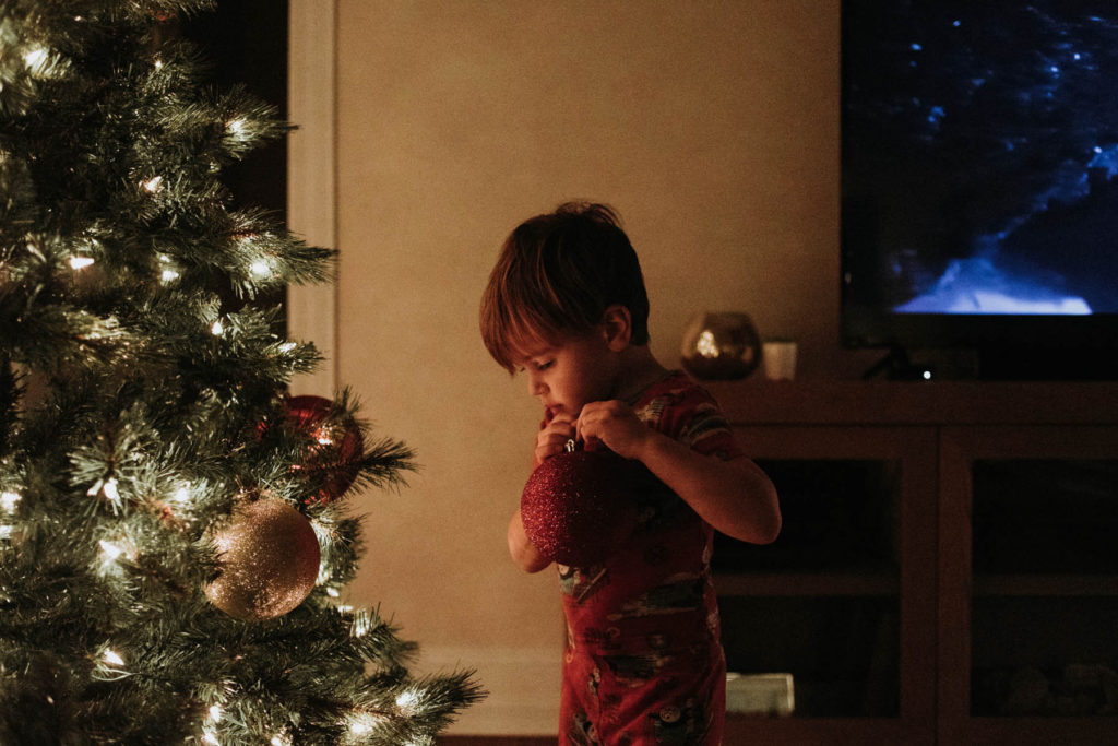 New Lenox, Illinois Family Photographer, Photo by Elle Baker Photography, boy hanging a red ornament on a Christmas tree