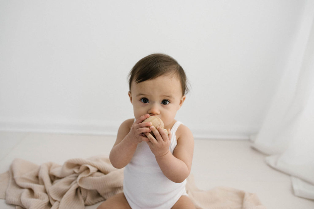 Simple and natural baby session, Photo by Elle Baker Photography, baby girl in white studio space in Chicago using a wooden teether