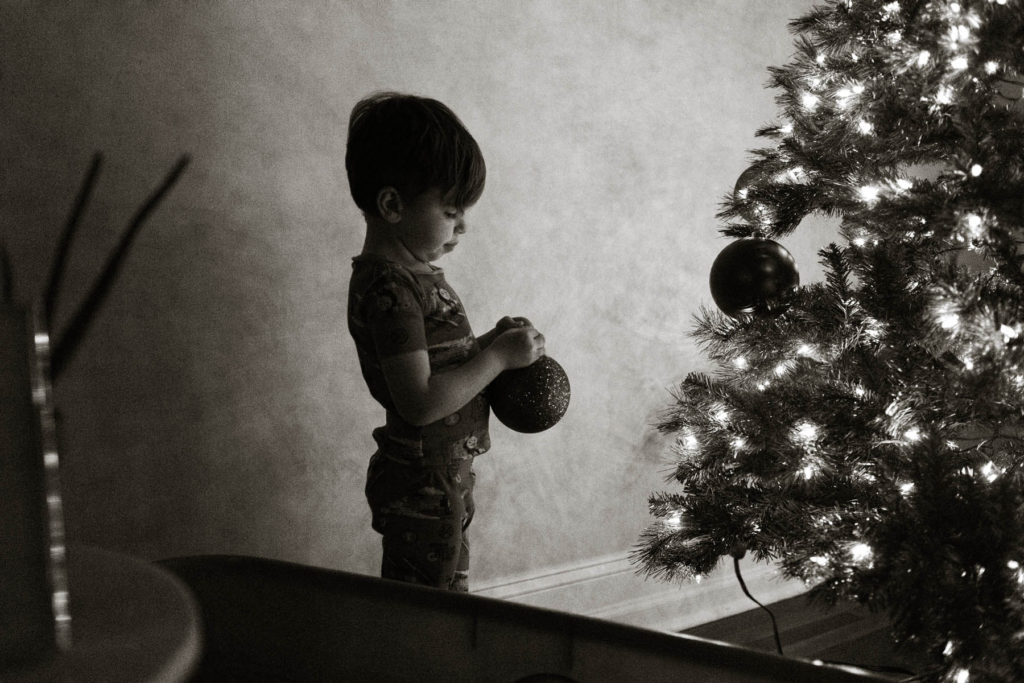 New Lenox, Illinois Family Photographer, Photo by Elle Baker Photography, boy hanging a red ornament on a Christmas tree