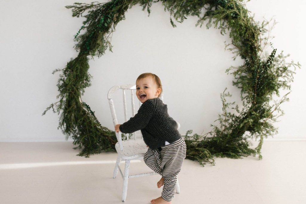 Homer Glen, IL Holiday Mini Sessions, Photo by Elle Baker Photography, boy posing with large wreath during Christmas session