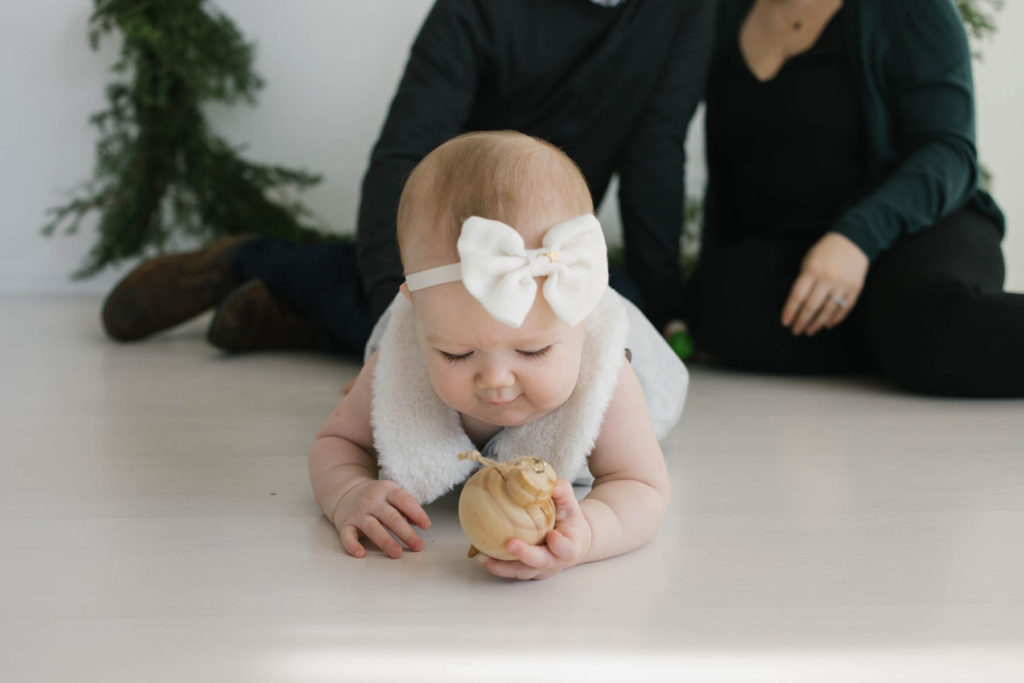How to pose large families in small spaces, Frankfort IL family photographer, Elle Baker Photography, baby girl with large bow playing with wooden ornament
