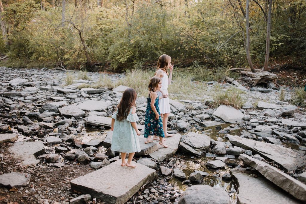 Natural and candid family photography, photo by Elle Baker Photography, three sisters walking in river bed