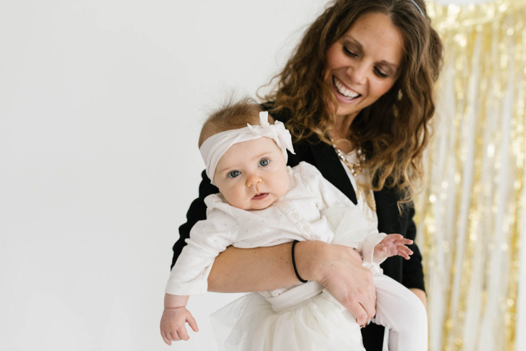 New Year's Photo Session, Photos by Elle Baker Photography, mom holds baby girl with gold streamers during studio session