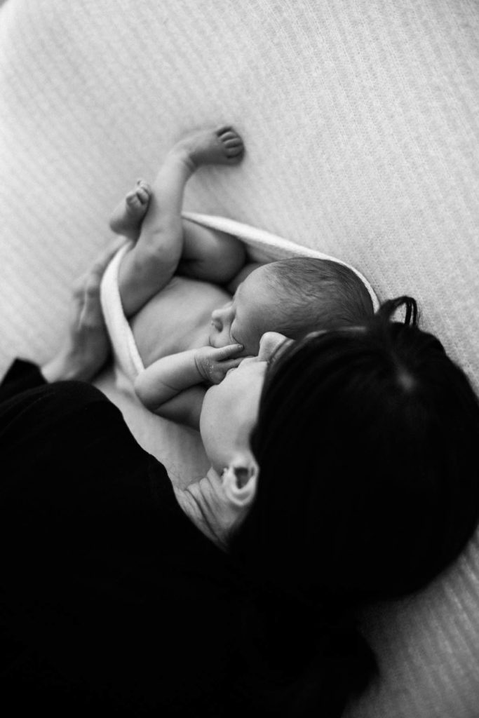 black and white image of mother laying next to newborn baby boy