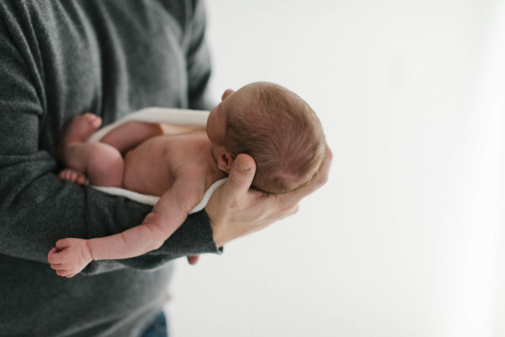 Chicago newborn photographer, Elle Baker Photography captures beautiful simple image of father holding newborn baby in arms