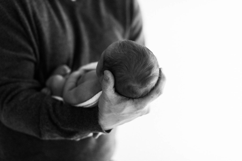 black and white image of father holding newborn baby in his arms