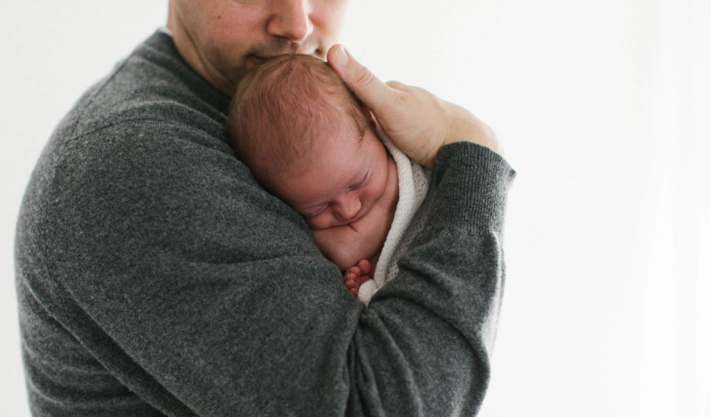 newborn baby boy being held by his father in his arms