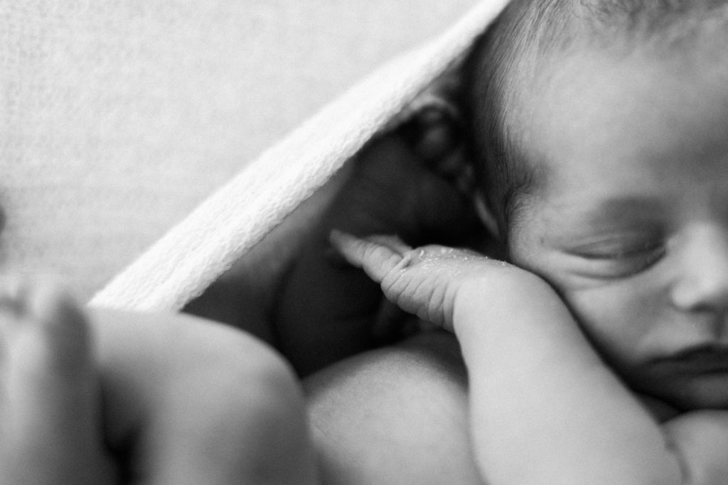 black and white image of a newborn baby's hand and finger