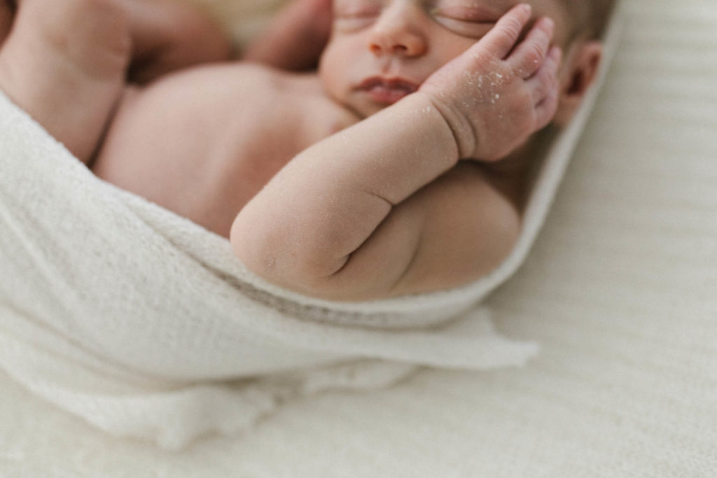 Close detail shot of a newborn baby's elbow and flakes of skin on his small hands