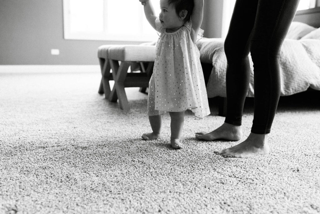 black and white image of a mother holding her daughters hands 