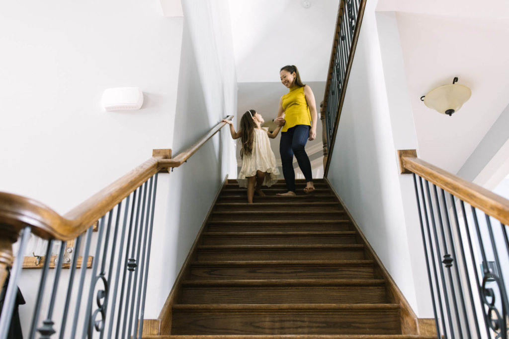 mom and daughter step down their stairs from the upstairs