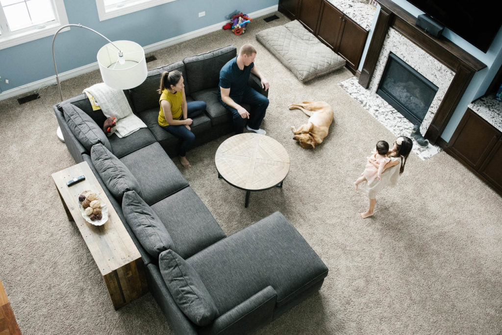 family of four hanging out in their family room with dog rolling around 