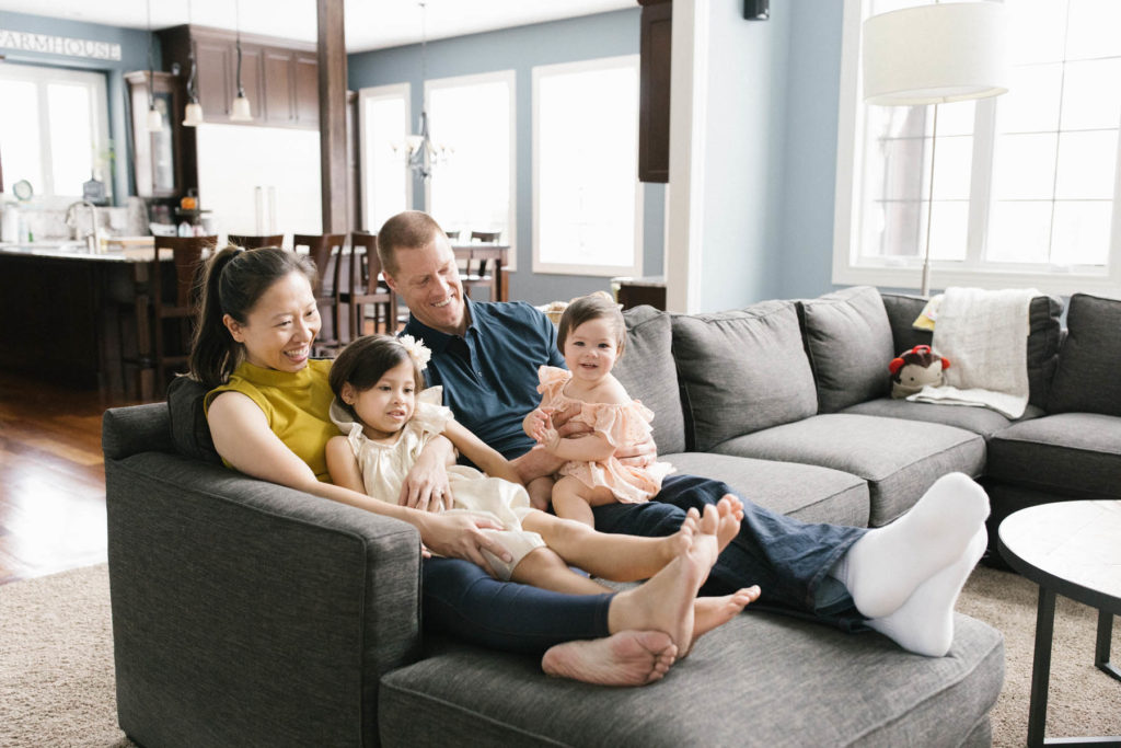 family of four sits on sofa in their family room 