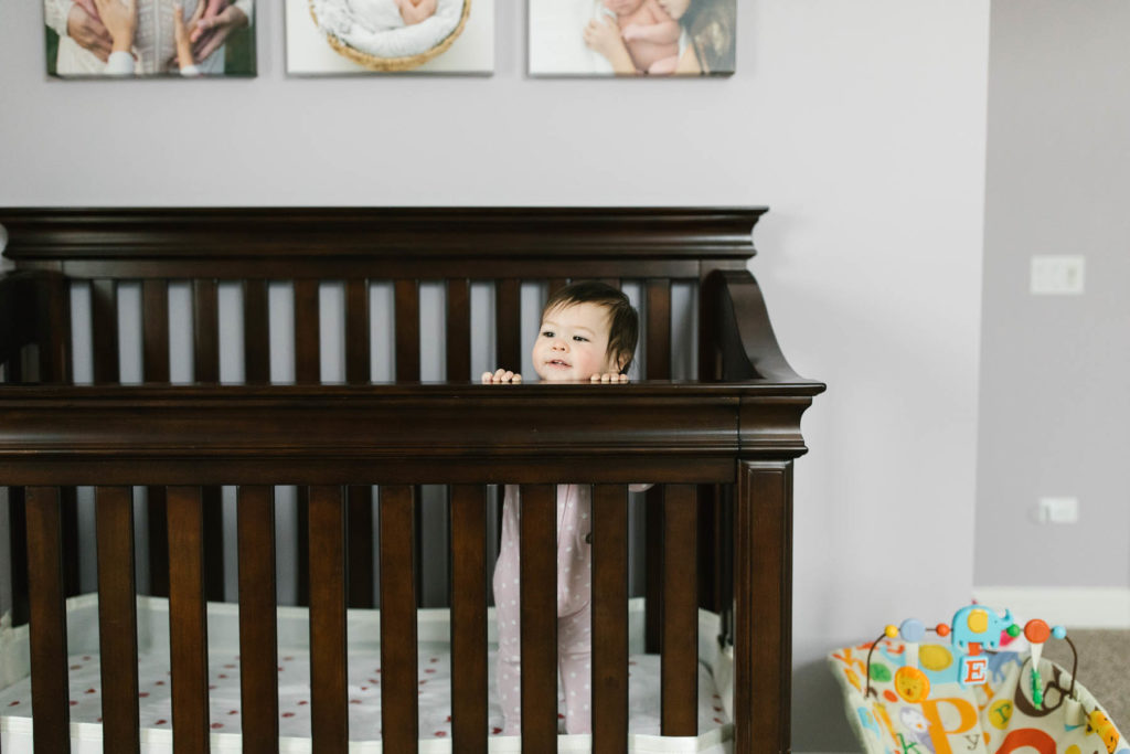 baby girl looking over the edge of her crib 