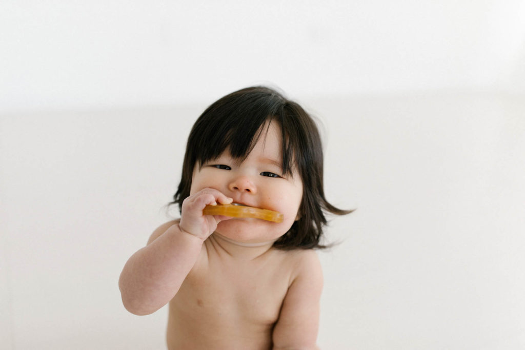 close up photo of a little girl chewing on a teether toy