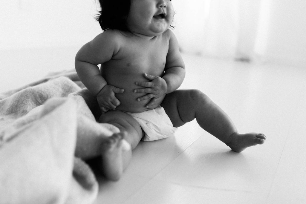 black and white image of a baby girl grasping her belly