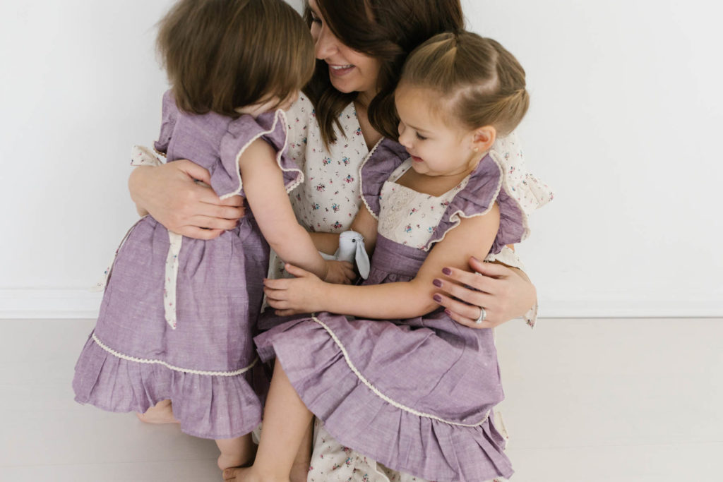 Mom and two daughters embrace and laugh during session with family photographer Laurie Baker