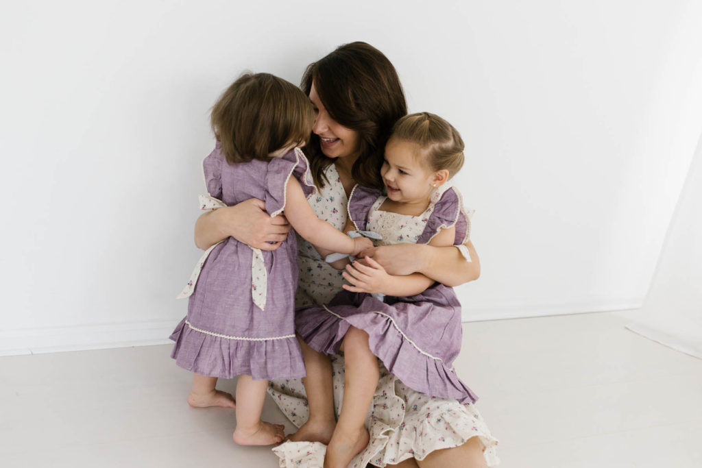 mom candidly plays with her two daughters in lilac dresses by Ele Story