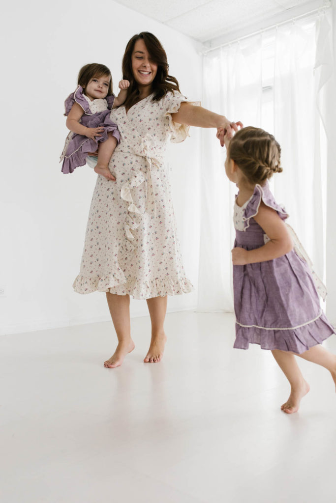 mom holding her daughters hands twirling in white studio Chicago 