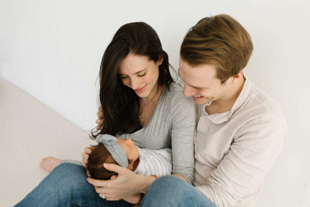 parents holding newborn baby and smiling 