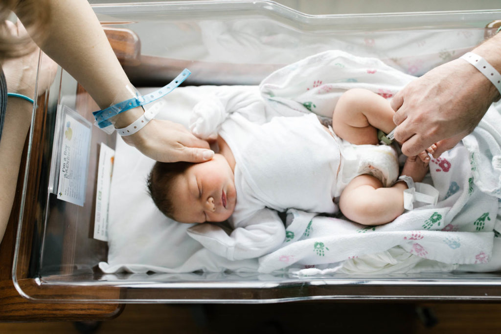 parents touch newborn baby in hospital bassinet during Fresh 48 hospital session with Elle Baker Photography 