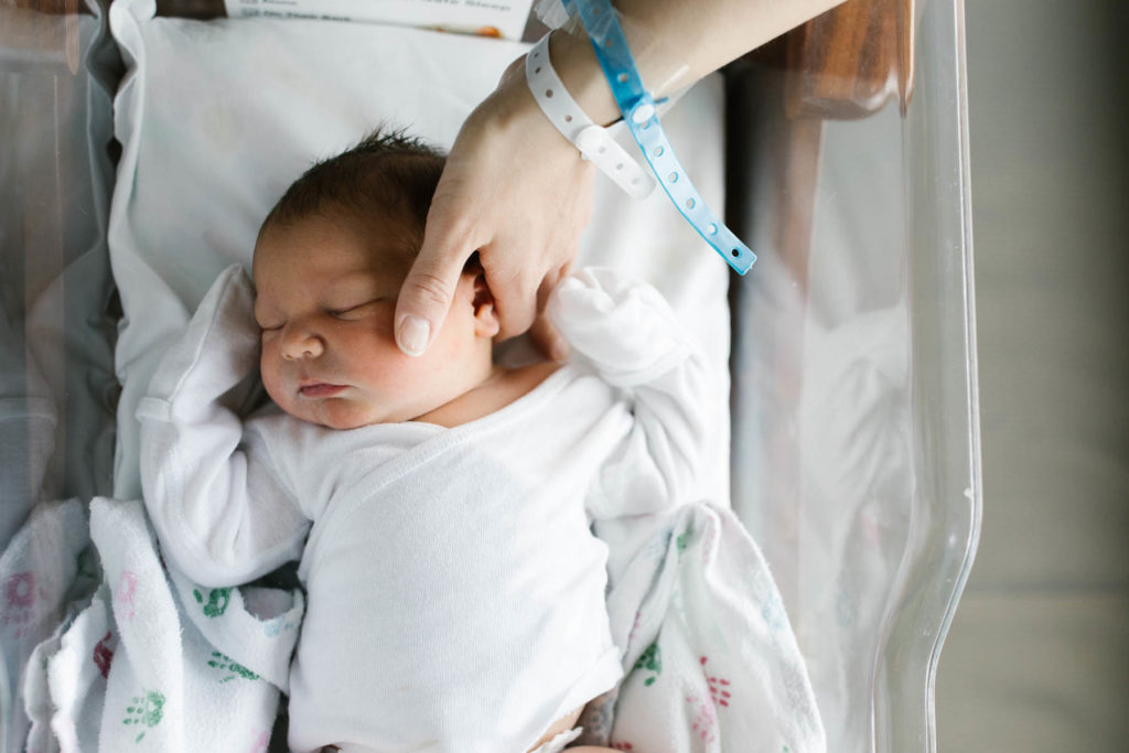 mother soothes her newborn wearing hospital bracelets 24 hours after birth 