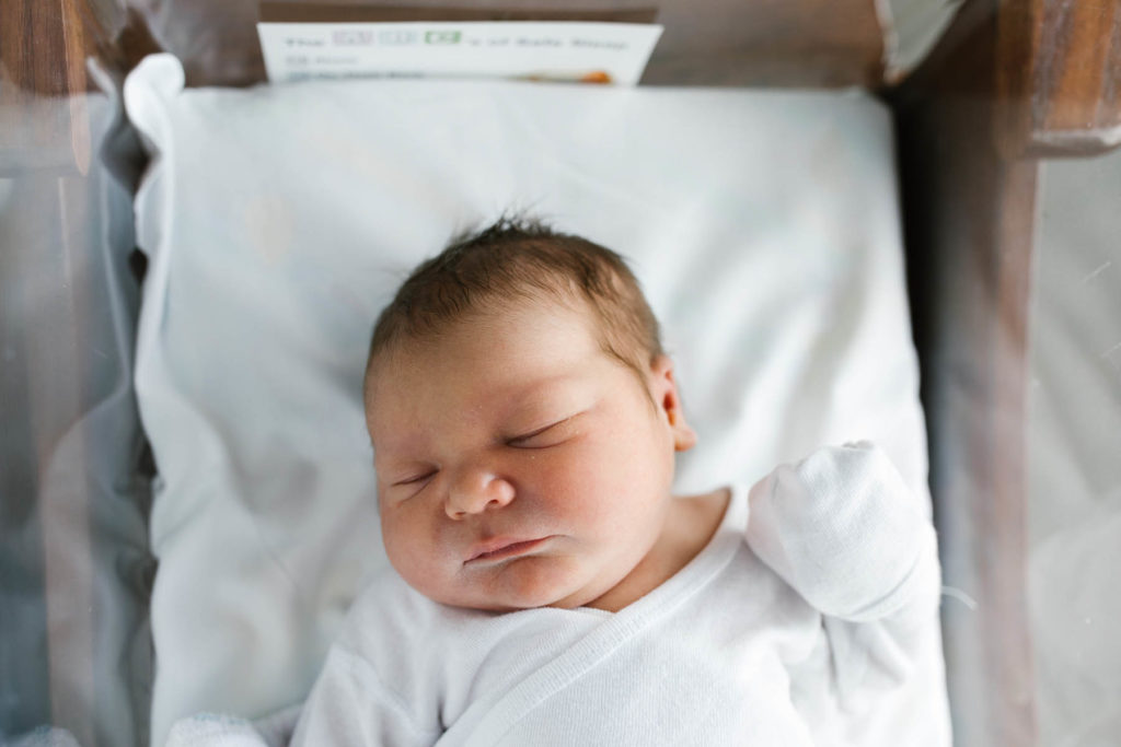 Newborn baby boy laying in bassinet during newborn session 