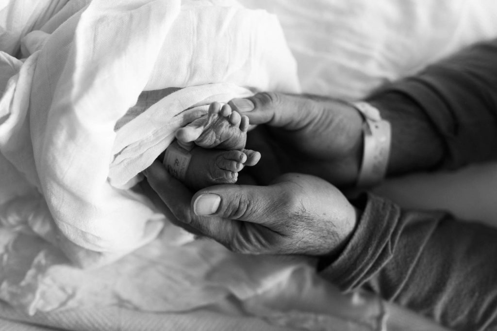 Father holding his newborn baby boys feet during Fresh 48 hospital newborn session 