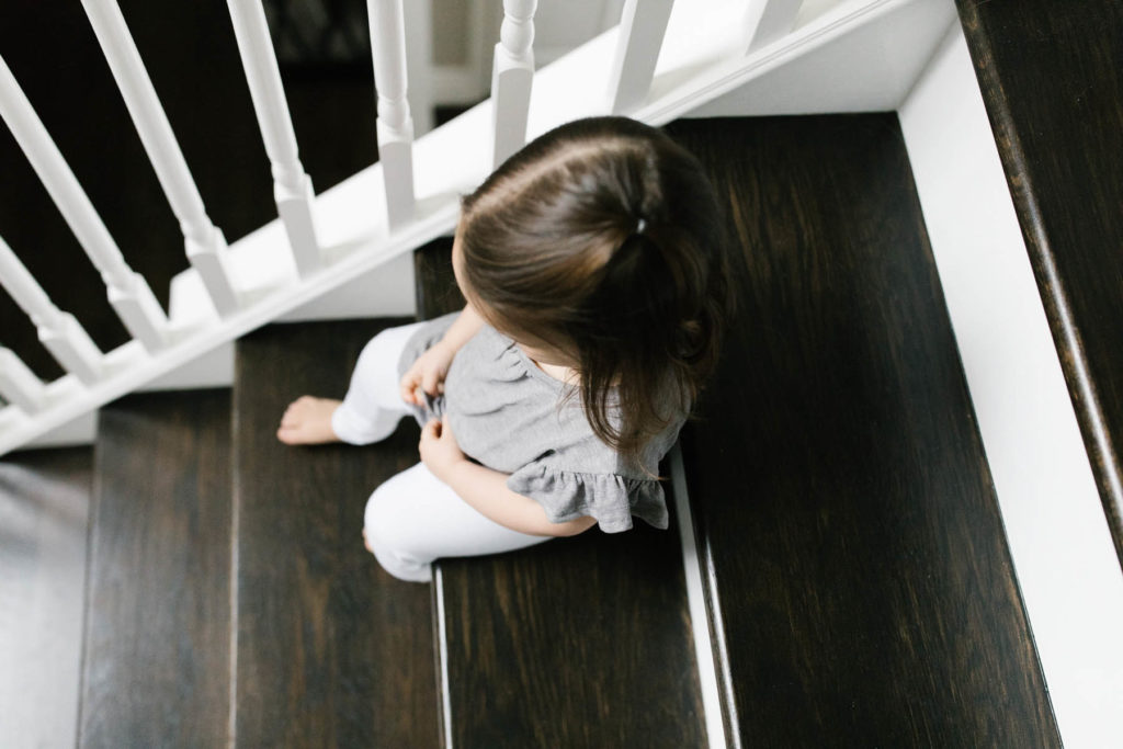toddler girl sits on stairs in Downers Grove home, photographed by Elle Baker Photography