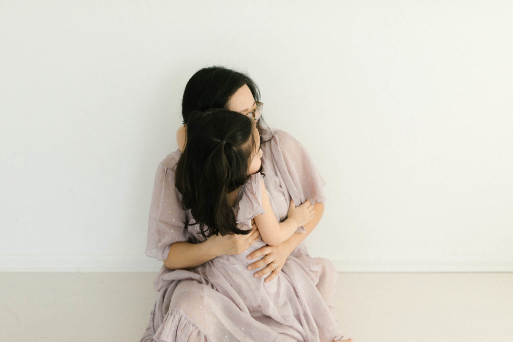 mother and daughter in purple dresses embrace 