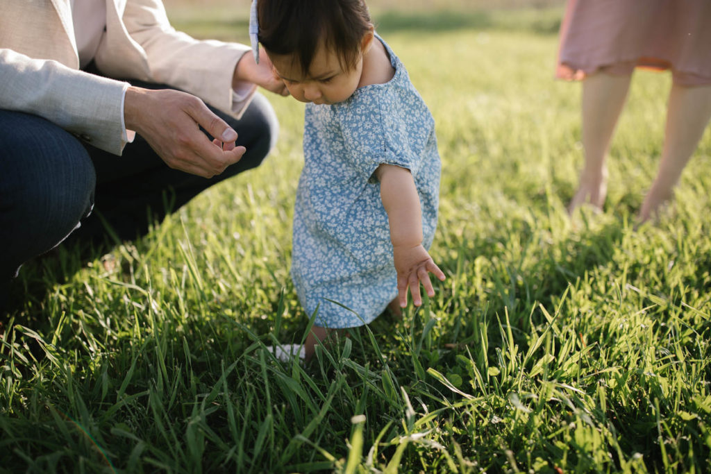 Little girl touching grass for the first time, photographed by Elle Baker Photography at Mokena IL forest preserve