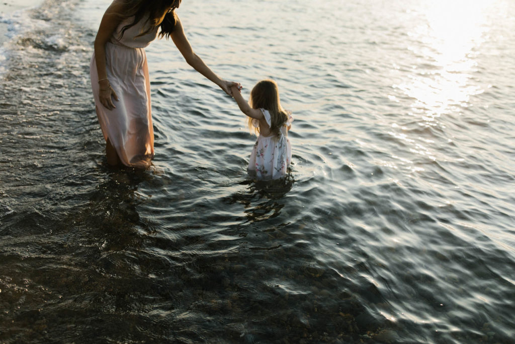 mother helping daughter out of water at a beach session with Elle Baker Photography 