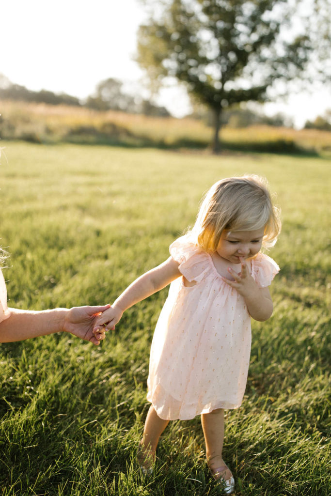 toddler holding mom's hand during photography session