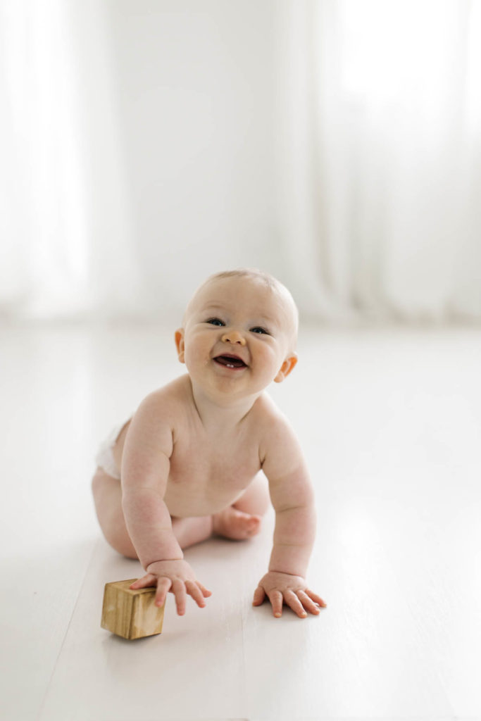 baby boy crawling and laughing during six month photo shoot