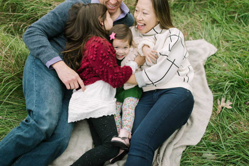 the family laughs as they play on a blanket 